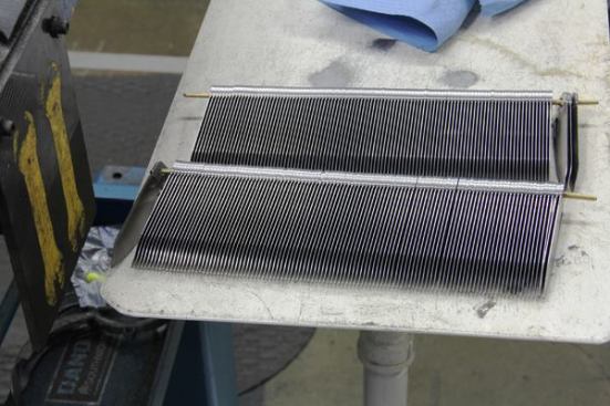 These are the knife blades you saw in the previous photo. They have been strung onto a metal rod that will be placed into a fixture within reach of the industrial robot that will grind them to their final shape.