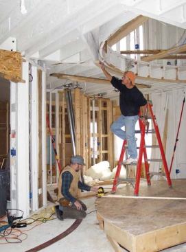 A carpenter shifts the position of the top plate so it’s in line with the beam that projects up from the laser.
