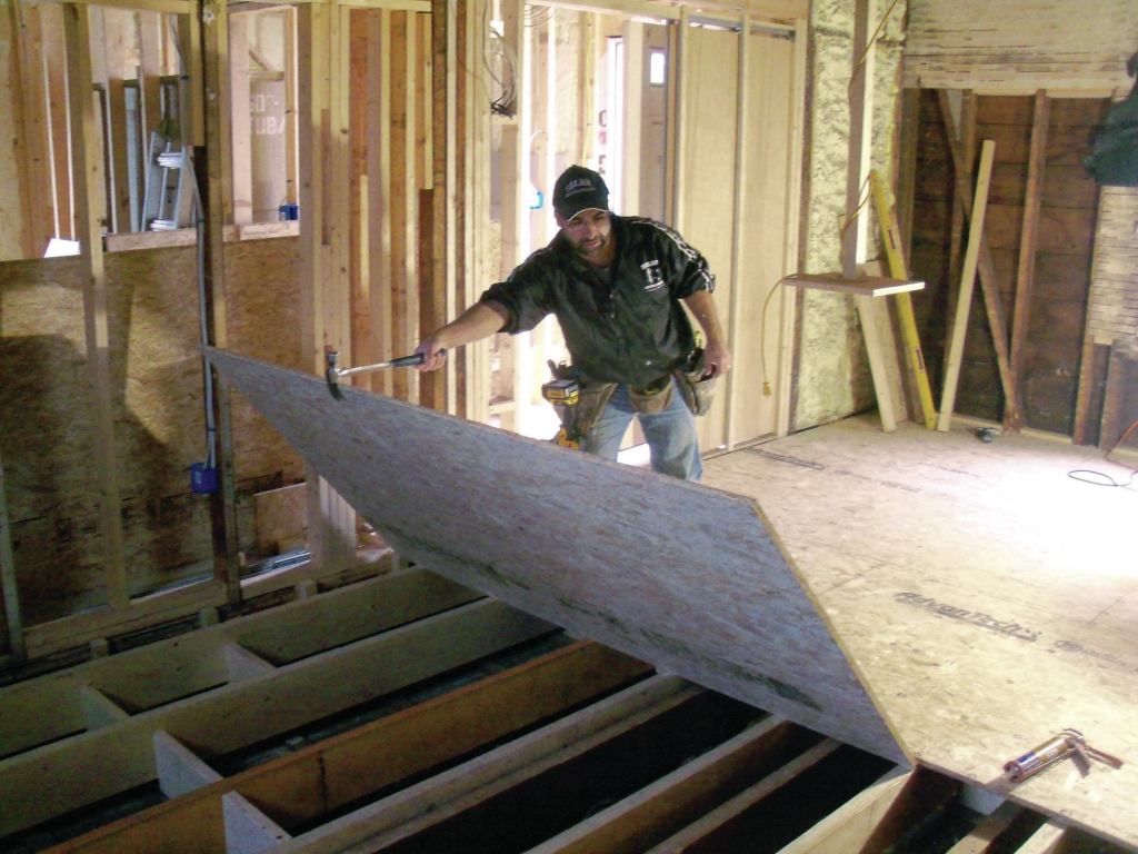 Finally, I insulated the ends of each joist bay against the outside wall with fiberglass batts. To complete the floor system, I glued and screwed 3/4-inch OSB subfloor to the joists, staggering the end seams as I went along (18). In the end, the extra time I spent paid off. The floor was completely flat, level, and solid as a rock—a perfect foundation for the new kitchen cabinets.