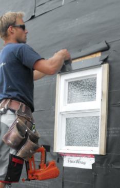 After cutting the paper above the window at 45 degrees and folding it up out of the way, I tuck in the flashing and nail it directly to the sheathing with the same 2-inch nails I used for the window flanges.
