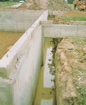 A short reinforced concrete wall has been formed and cast to span the distance from its footing to the adjoining wall (the trench will be backfilled as usual).