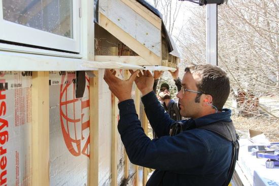The tongue-and-groove soffit board material was pre-painted with one coat of exterior latex prior to installation. Here the crew is lining up the miter at the outside corner, then marking the other end to be cut to length.