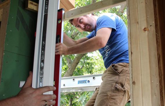 With the tilt-and-turn sash open, Smith checks the hinge side of the unit for plumb ...