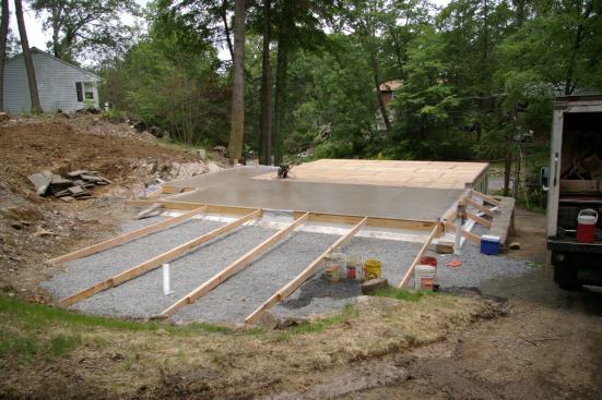 Drains that are under the crushed-stone base for the patio at the back of the house remove water that seeps down the sloped lot. Gutter leaders from the long south-facing roof will also tie into the same system.