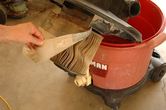 Riveting a plastic flap between the vac's hose inlet and the filter helps keep the filter dry and free from muck during wet cleanup. For dry vacuuming, the flap protects the paper filter from incoming jagged debris.