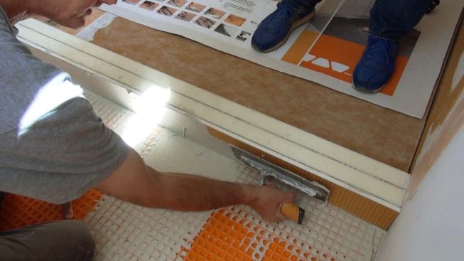 Boucher applies mortar to the polyethylene face of the Kerdi-Board curb.