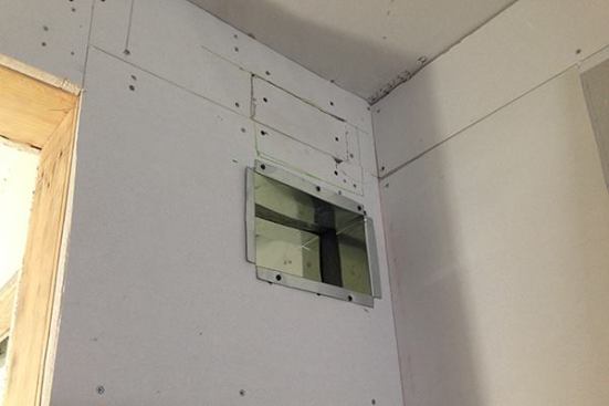 The metal duct register shown here is one end of a pass-through vent set in the master bedroom to help move return air from the bedroom into the hallway, where the ducted mini-split system’s return grille is located. The other end of the pass-through vent is located in a hallway closet with a louvered door.