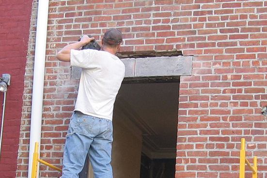 With the interior wythe of brick supported by the first steel channel, workers can safely remove the stone lintels and exterior brick.