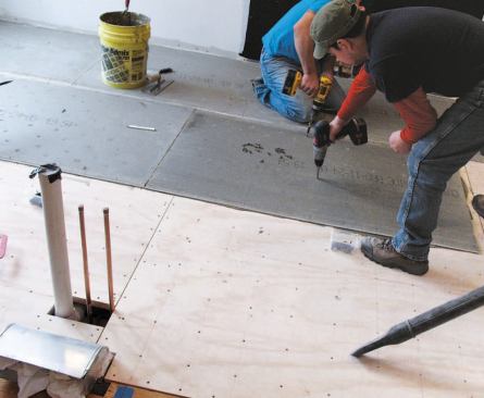 Workers screwed down 1/4-inch backerboard.