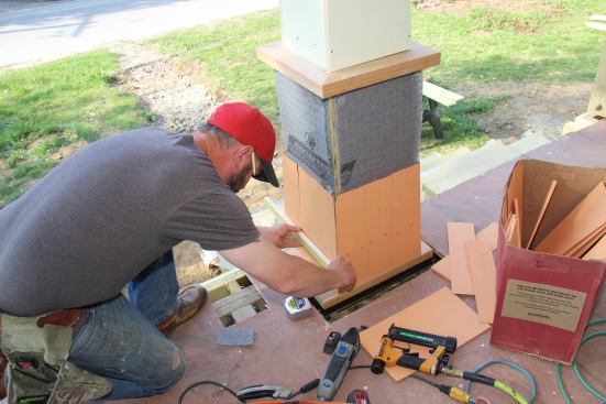 Shane Fenton tacks on a strip to set the location for his next course of pre-primed cedar shingles.
