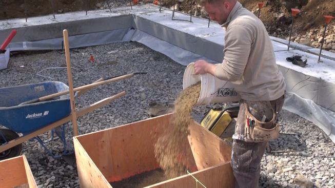 Adding sand to the form. Sand serves to protect the relatively fragile Foamglas and provide a smooth, flat cushion of support for the insulating material.
