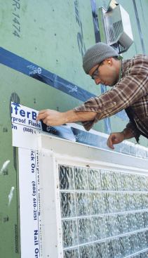 A worker seals a metal cap flashing with Zip tape.