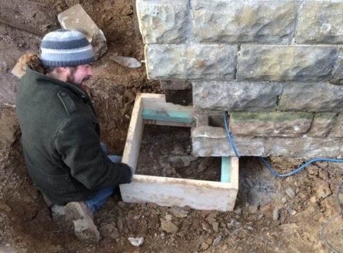 Martignetti sets a wooden footing form under the foundation. The plan is to dig and form up footings in short sections, pour a section of concrete footing and let it set, then excavate and underpin the next short section, and so on.