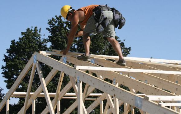 Two skilled carpenters handle the “leading edge” work at the top of the trusses, installing spacers and bracing and unhooking each truss from the crane after it is set.