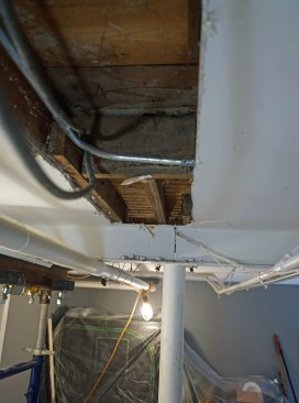 From the basement we are looking into a joist bay in the first floor. A new steel beam will be installed perpendicular to this basement I-beam girder. The new steel beam will span from this girder to a second basement girder that runs parallel to this one in the background.
