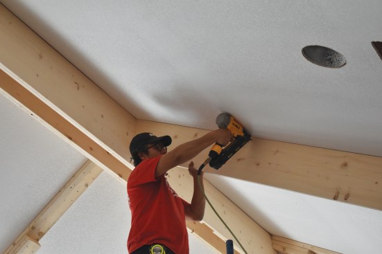 Ensuring the cut beam panels remain straight during install is a two-person job. Shims are used as needed while panels are being nailed to the blocking.