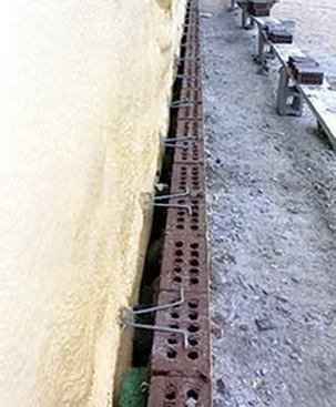 The rainscreen wall system in this commercial project uses a layer of closed-cell foam and an outer layer of brick veneer, separated by an air space. The outer skin of the foam serves as the drainage plane, while its inner face — sprayed against fiberglass-reinforced gypsum board on steel studs — acts as a vapor barrier.