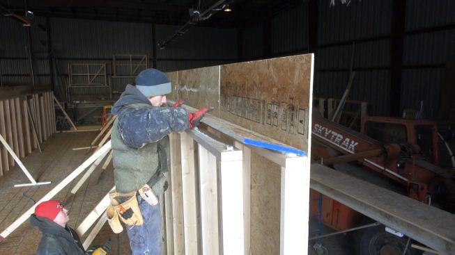 A worker in the VerMod plant applies the OSB top plate to a unit's 10-inch-thick double stud wall. The thin OSB plate minimizes thermal bridging at this location. "Optimum Value Framing" methods are used throughout the unit's shell, according to VerMod executive Chet Pasho.