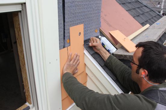 Pollard holds a shingle in place and freehand-scribes the profile of the adjacent roof edge onto the shingle.