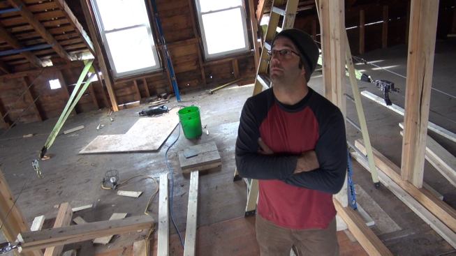 Mark Pollard surveys the complex framing of the old house roof, which has to be pulled back into shape, reinforced, and deepened to allow above-code levels of insulation. At left rear is a set of come-alongs used to haul inward on the house’s balloon-framed kneewalls, which had deflected out severely over a century of service. Coastal Connection will take a closer look at the roof re-framing and envelope energy detailing in a future issue.