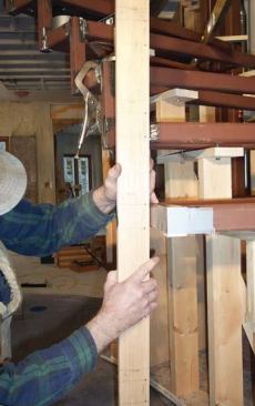 With the frame positioned horizontally in space, he checks its height against the story pole.