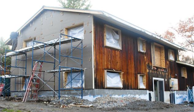 After removing the old windows and installing plywood window bucks, workers wrapped the walls with 4x8 panels of 4-inch-thick polyisocyanurate foam.