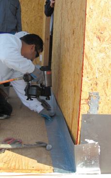 The flanges are nailed to the deck and wall. When the building paper is installed, it will lap the flashing shingle-style.