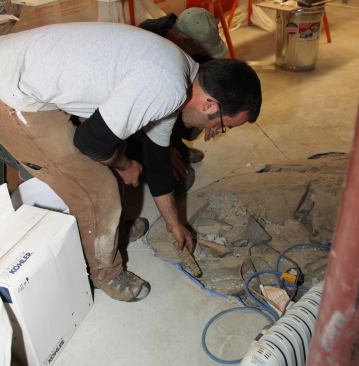 Smoke curls up from a leak in the basement floor at the joint where a newly placed slab meets existing stone ledge. Some of the home’s air infiltration, measured by the blower door test, occurred at this crack in the floor. When the home is in operation, however, a fan connected to sub-slab perforated piping will likely pull indoor air into the sub-slab gravel bed through this crack, rather than allow soil gas to enter the home.