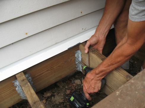 The original joist hangers were still in good shape, but only nailed in place with a few roofing nails. The author replaced the undersized nails with structural metal connector screws.