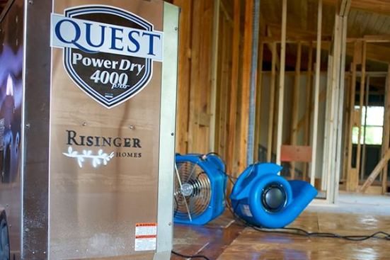 Quest PowerDry 4000 Dehum with Quest Air Mover fans running in the background drying a house in framing after a rain.