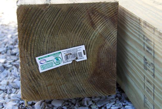 A view of the end of a fresh 2x6 treated-wood post on a job site in Massachusetts, showing the code-required wood-treatment label. This wood is approved for ground contact, like all treated 4x4 and 6x6 lumber in today’s market. (However, cut ends must be field-treated with a copper naphthenate solution in order to maintain warranty coverage, because the treating chemicals penetrate the wood from the inside out, and chemical concentrations are usually lower near the center of the piece.)