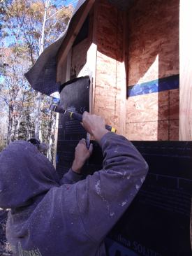 After the I-joists are affixed outboard of the stud wall, a drainage plane of Solitex Mento Plus "sarking membrane" is stapled onto the outer edge of the I-joists. This waterproof but breathable fabric will shed incidental water that may get behind the wall siding, and will allow the wall to dry to the outside.