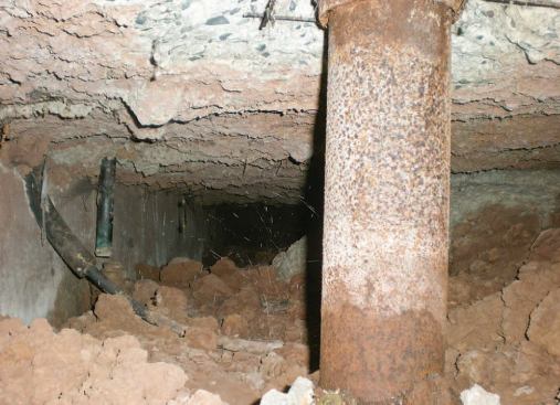 The inspection hole allowed the author to take this photo, which shows a large gap between the slab and the soil beneath and, at the back, a disconnected waste line.