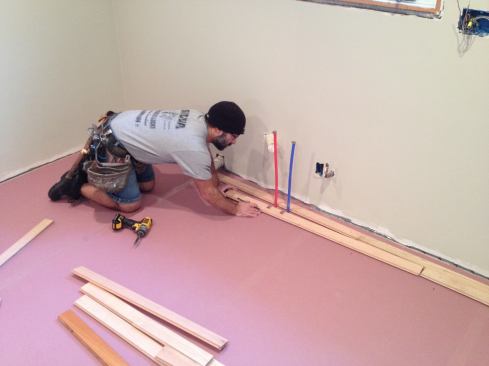 Cutouts have to be made for any through-floor obstructions such as the plumbing pipes. Manny cuts the pieces and makes a dry fit before nailing them into place.