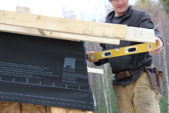 Checking the relationship between the lower edge of the overhang framing and the wall face.