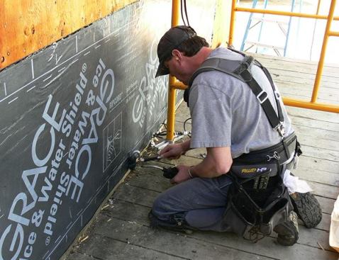 Carpenter Rich Perry uses a heat torch and roller to make sure the bituminous membrane adheres fully in the cold temperatures.
