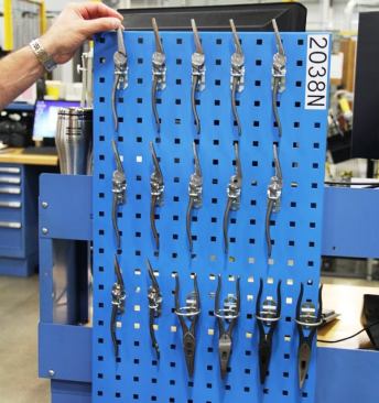This sample board shows long-nose pliers at various states of finish. The piece on the top left is a raw forging as it enters the plant. From there it goes through various machining operations, heat treating, assembly, and polishing. The pliers on the bottom right are ready to received dipped or molded handles.