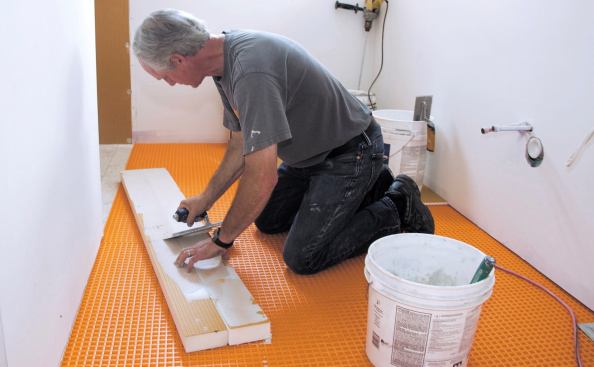 Boucher works mortar into the faces of the Kerdi-Board pieces. Pressing the mortar into the Kerdi-Board is important for achieving a good bond. Once the mortar sets up and cures, separating the pieces will be virtually impossible.