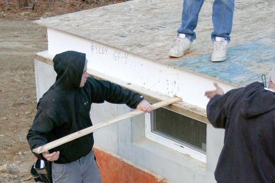 Prerouted grooves at panel edges receive 1/2-inch plywood splines, which the crew then staples at 4 inches on-center to stitch the panels together.
