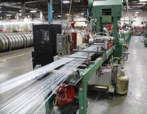 Here you can see multiple strands of wire being fed into the machine that glues them together and then rolls them into a coil. 
Click here for video.