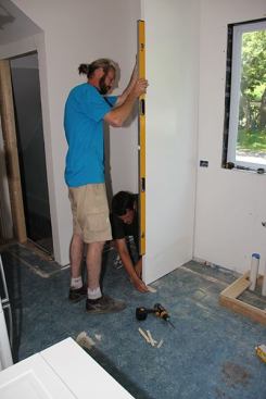 Jeff and Joe test-fit the end panel to the wall, shimming it plumb.
