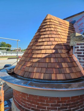 This photo shows the step flashing at the intersection of one turret and the central brick gable. Note the extended copper spout below the limestone capping. 