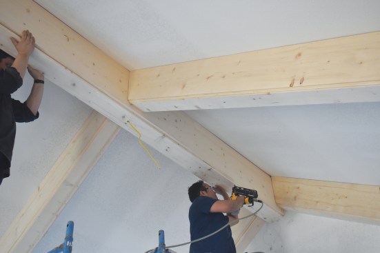 Teamwork is needed again as the bottom panels are attached to the preinstalled backing while the crew uses a 3/4-inch scrap to maintain spacing.