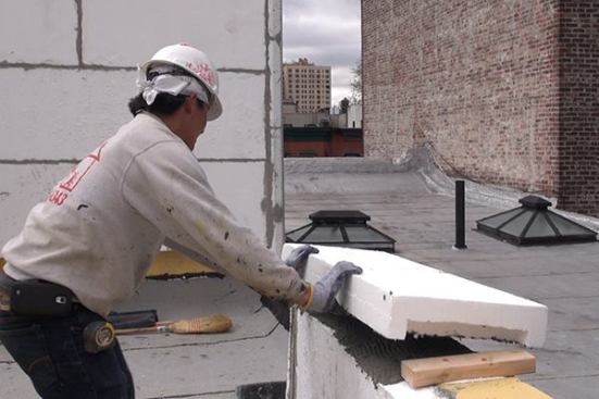 … before being set onto the poured concrete cap of a reinforced masonry parapet wall.