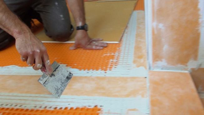 Boucher presses the Kerdi membrane into the mortar bed with his customized drywall knife.