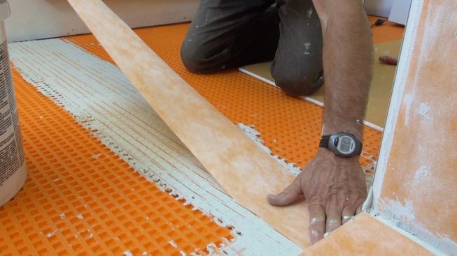 Boucher presses a strip of Kerdi membrane into the freshly applied mortar.