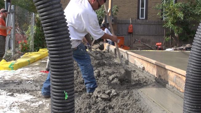 During an unexpected delay in the arrival of the third concrete truck, which got stuck in traffic, the concrete from the second truck began to harden. Here, workers roughen and work the concrete in hopes of preventing a cold joint.