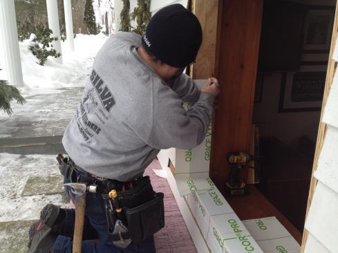 Covering the sides of the opening with flashing tape is easier if done in pieces. Here Manny makes an index mark for the top of the tape and marks the corner that will need to be cut.