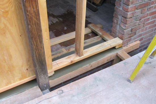 The old wall is capped with a new concrete sill to create a flat and level opening for the new door.
