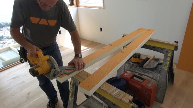 Boucher cuts two matching pieces of Kerdi-Board to length with a circular saw. The two pieces will be laminated face to face using cementitious mortar to create the shower curb.